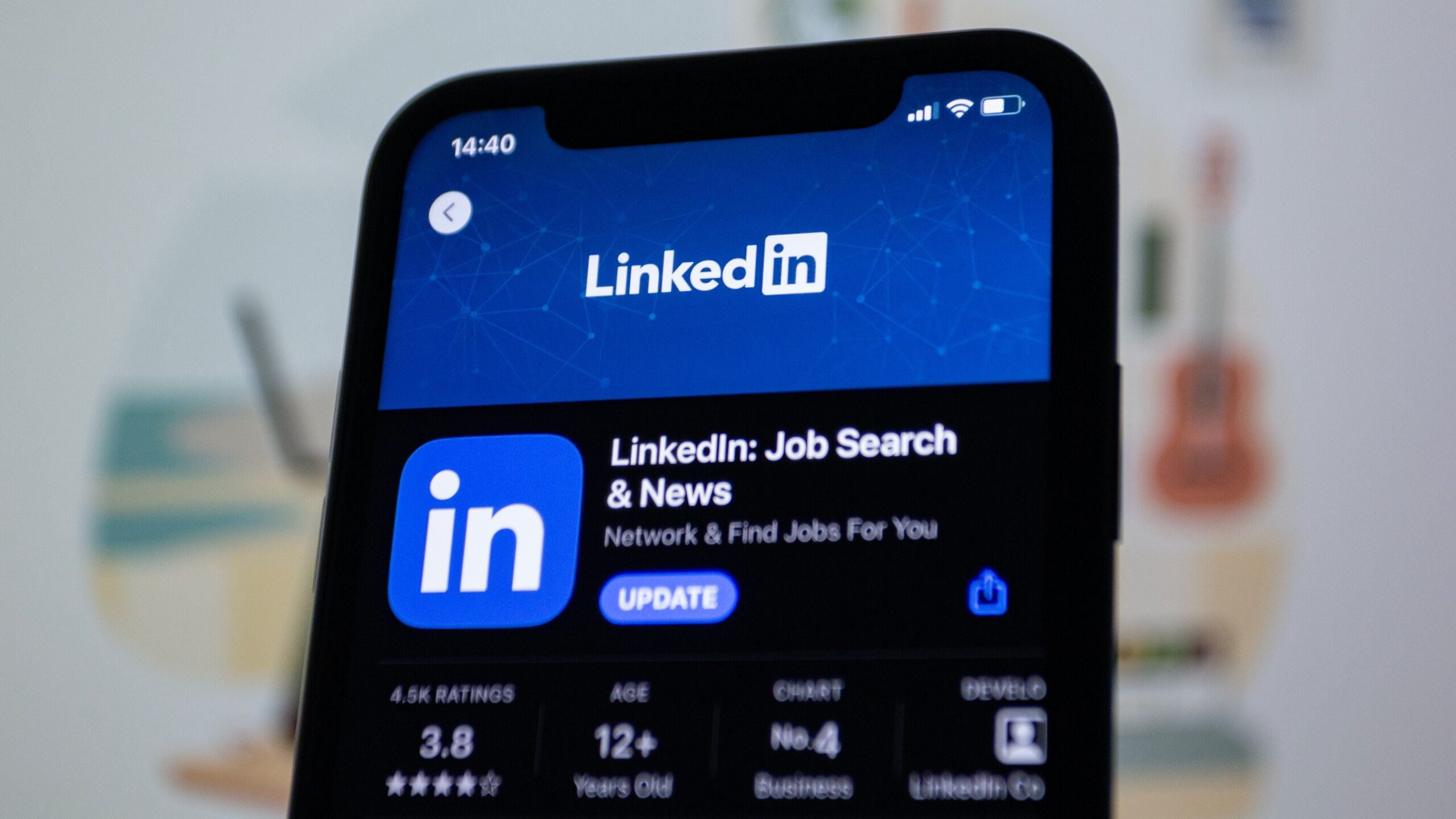 Blue LinkedIn logo on a cellular device opened to a job search and news profile.